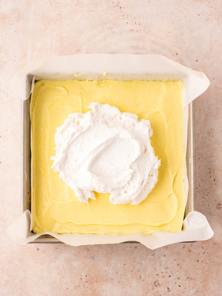 Whipped topping spooned over the firm pudding layer in a square baking pan.