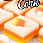 Close-up of neat fudge squares topped with candy corn, arranged in rows on a marble surface with orange napkin accents.