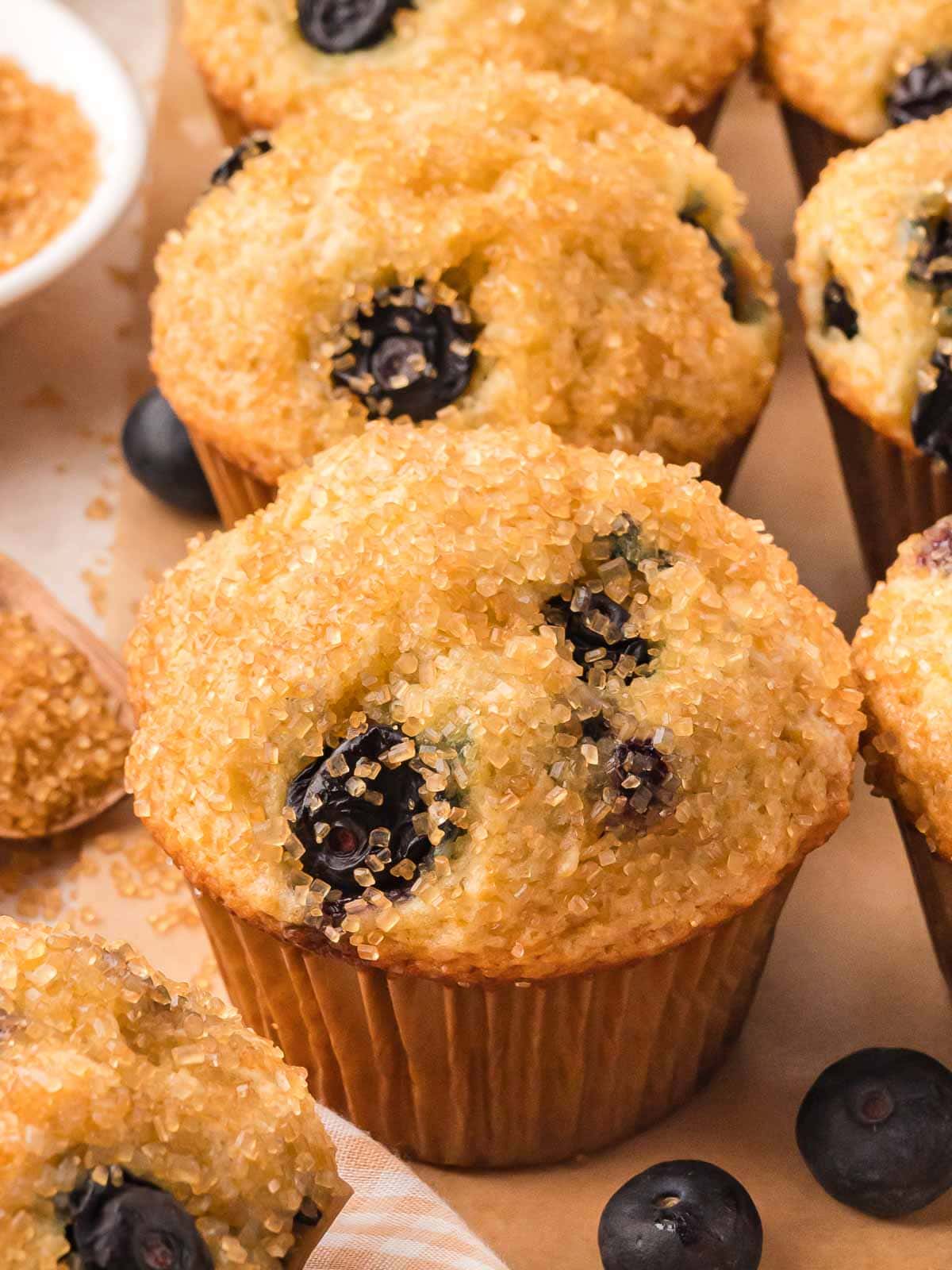 Close-up of a fluffy blueberry muffin topped with coarse sugar and juicy blueberries, fresh from the oven.