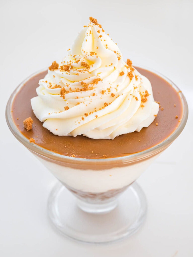 Whipped cream on top of the biscoff cheesecake cup with crushed biscoff cookies sprinkled on top.