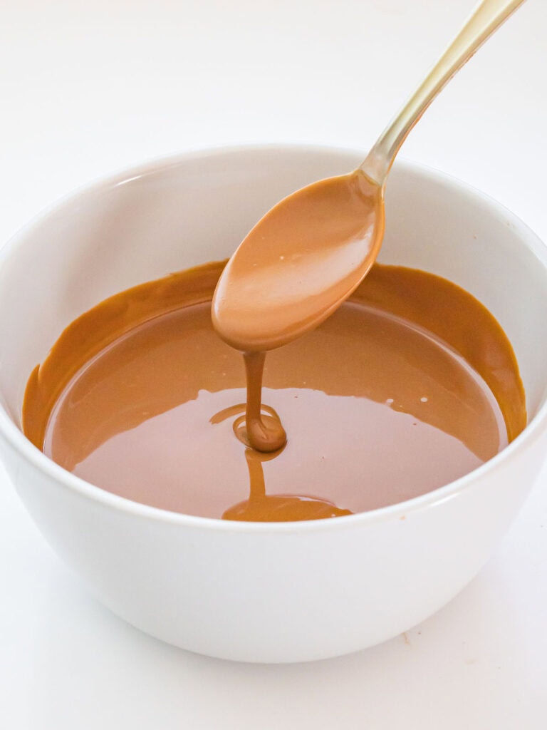 A spoon pouring biscoff cookie butter into a bowl.