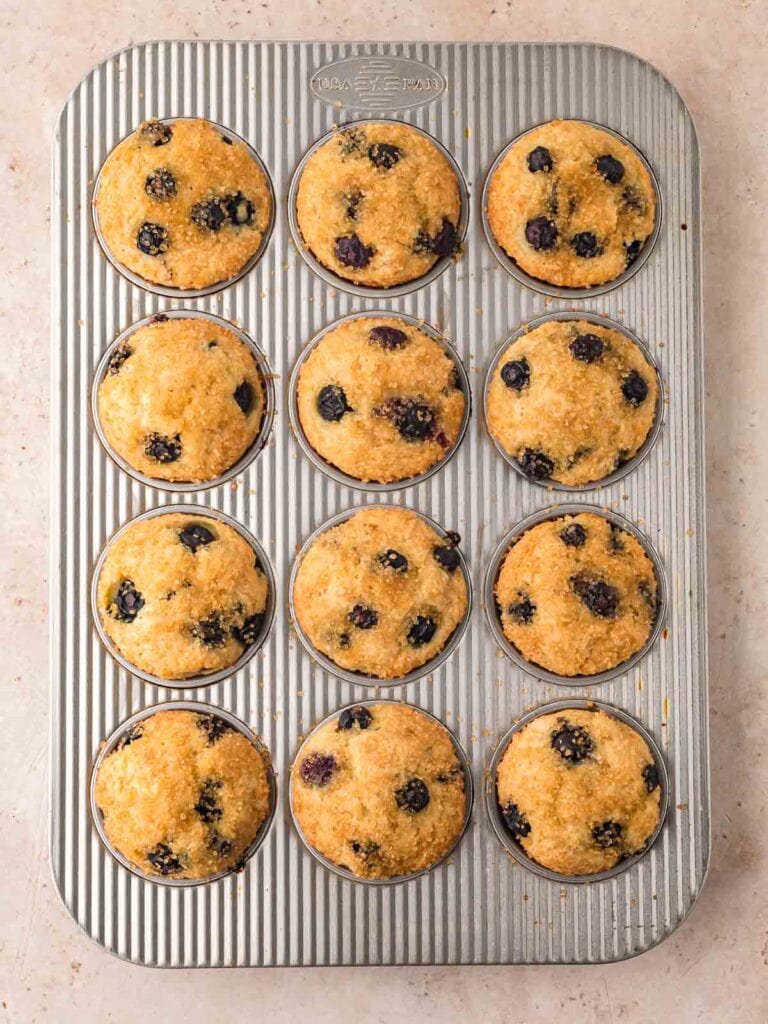 Golden, bakery-style blueberry muffins with crunchy sugar tops fresh from the oven.