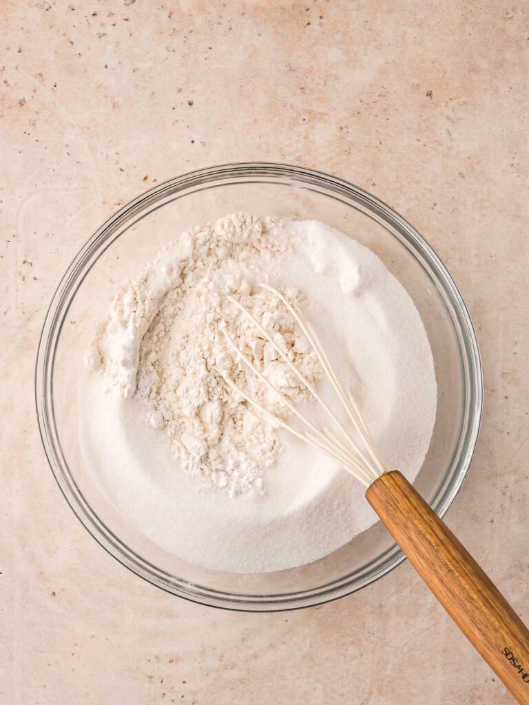 Bowl of flour and sugar being whisked together to start the muffin batter.
