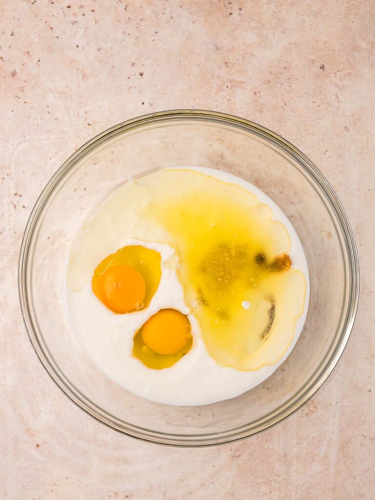 Bowl of eggs, buttermilk, oil, and vanilla ready to be mixed for blueberry muffins.