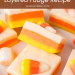 Squares of layered candy corn fudge with candy corn on top on a white surface by Tessie's Table.