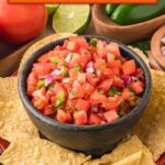 Single image poster of Fresh Tomato Salsa in a white bowl, styled with bold orange and red tones against a light background, featuring diced Roma tomatoes, jalapeño, and cilantro.