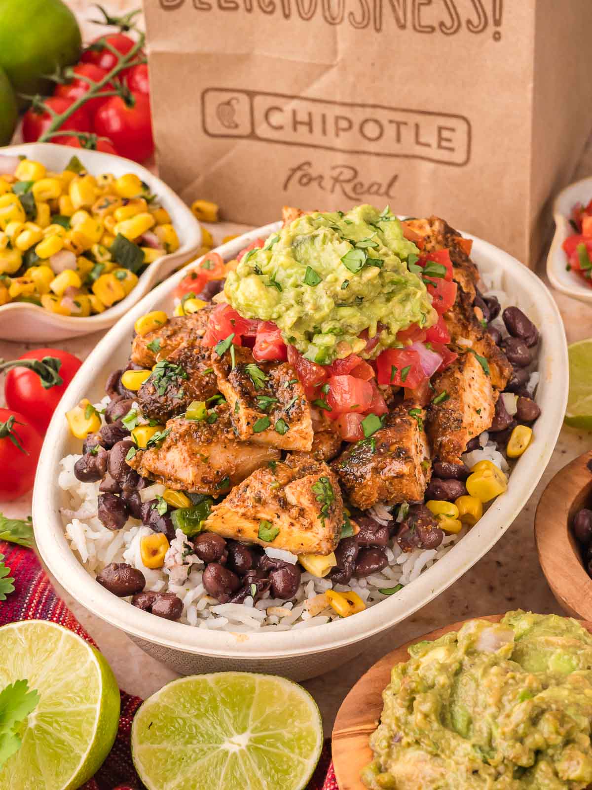 Copycat Chipotle burrito bowl in a takeout-style container filled with seasoned chicken, beans, rice, salsa, and guacamole.