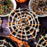Close-up of a Halloween Pretzel Spider Web made with pretzels, white chocolate, candy eyes, and colorful sprinkles.