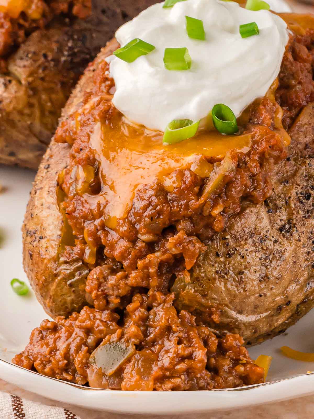 Sloppy Joe baked potato with cheddar cheese and sour cream, overflowing with saucy beef and peppers