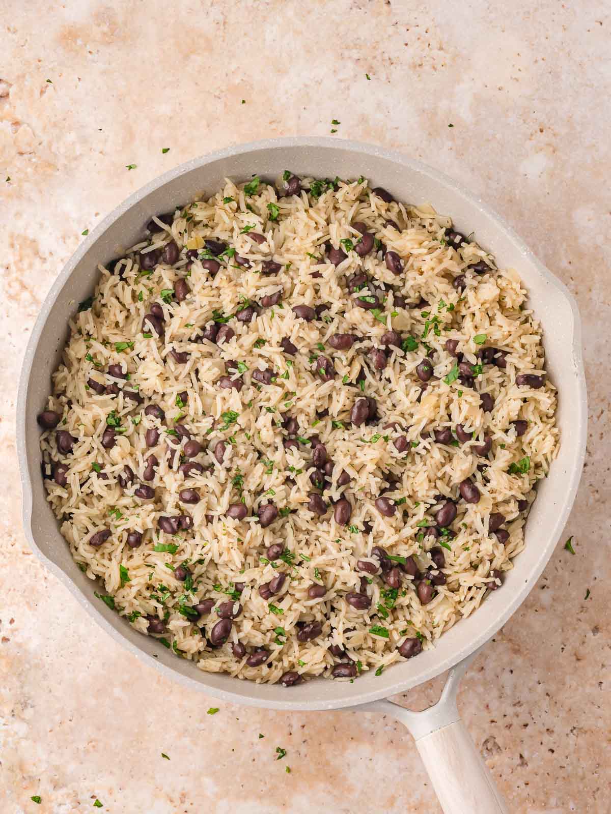Fully cooked black beans and rice in the skillet, fluffed and garnished with chopped fresh cilantro.