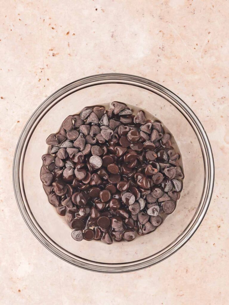 Semisweet chocolate chips in a clear glass bowl, prepared for melting to make sweet potato brownie batter.