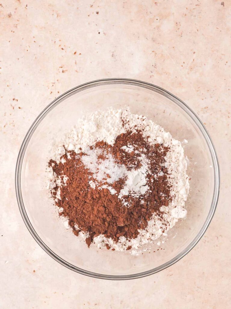 Dry ingredients including flour, cocoa powder, baking powder, and salt measured in a glass mixing bowl.