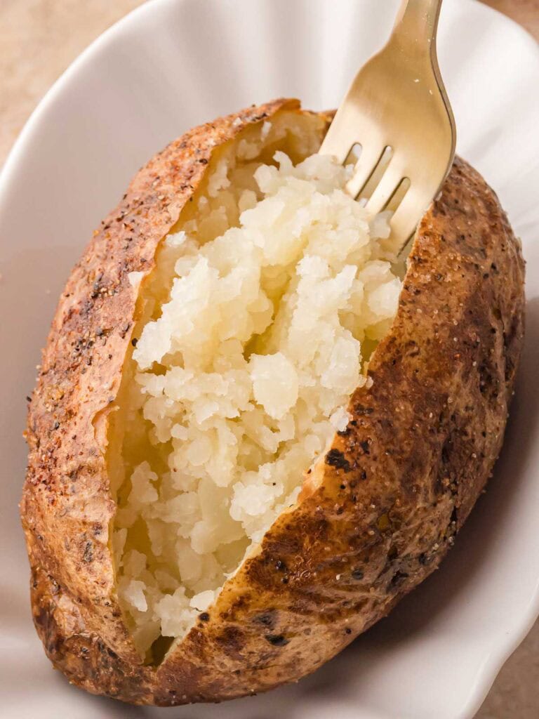 Crispy baked potato being fluffed with a fork
