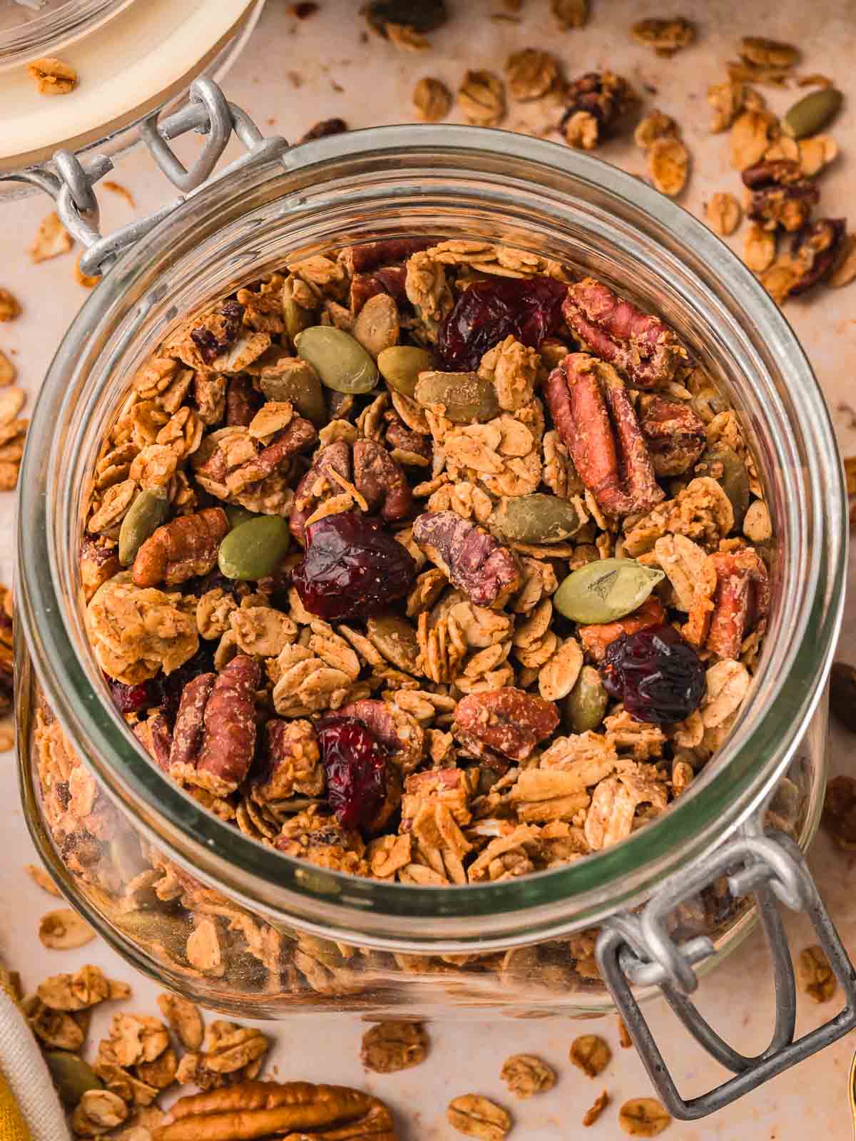 Glass jar filled with pumpkin granola made with oats, pecans, pumpkin seeds, and dried cranberries.