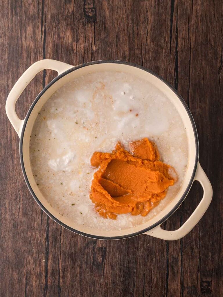 Pumpkin purée and coconut milk added to the pot with the sautéed aromatics, ready to be stirred into the soup.