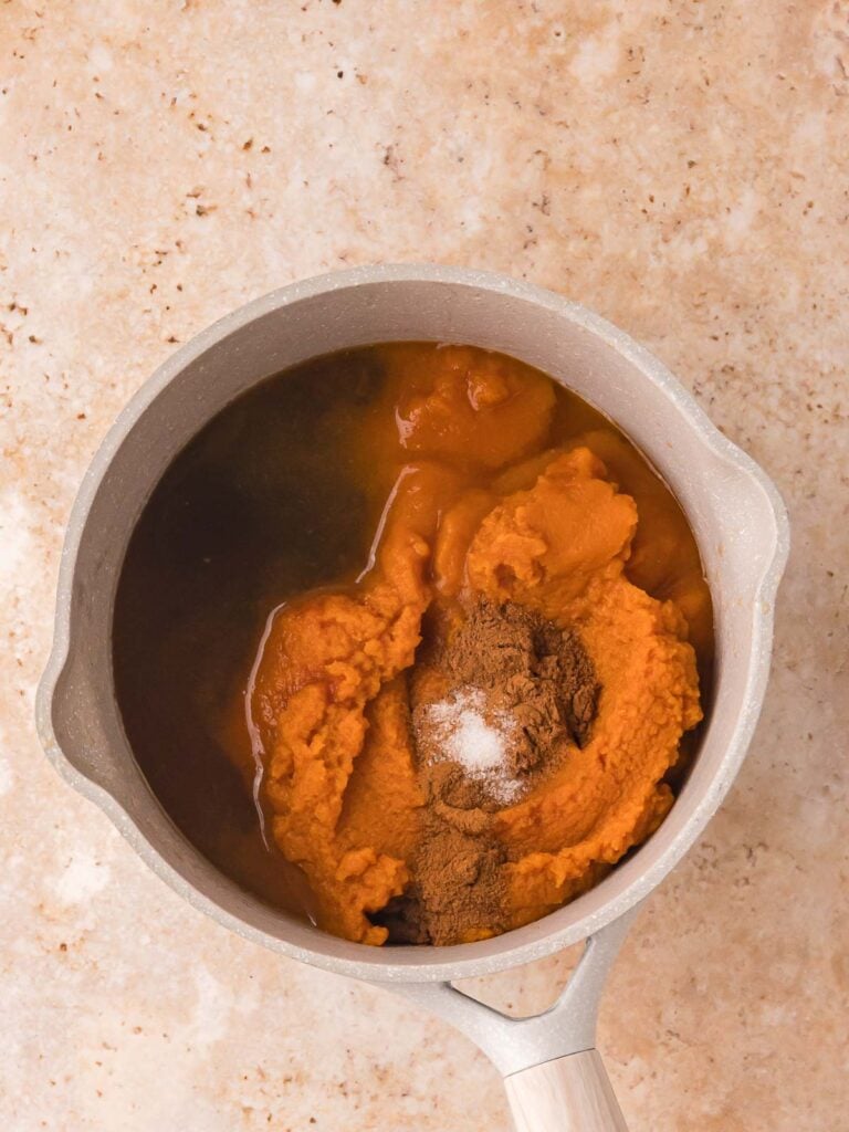 Unmixed pumpkin purée, apple juice, brown sugar, and spices in a saucepan before making pumpkin butter.