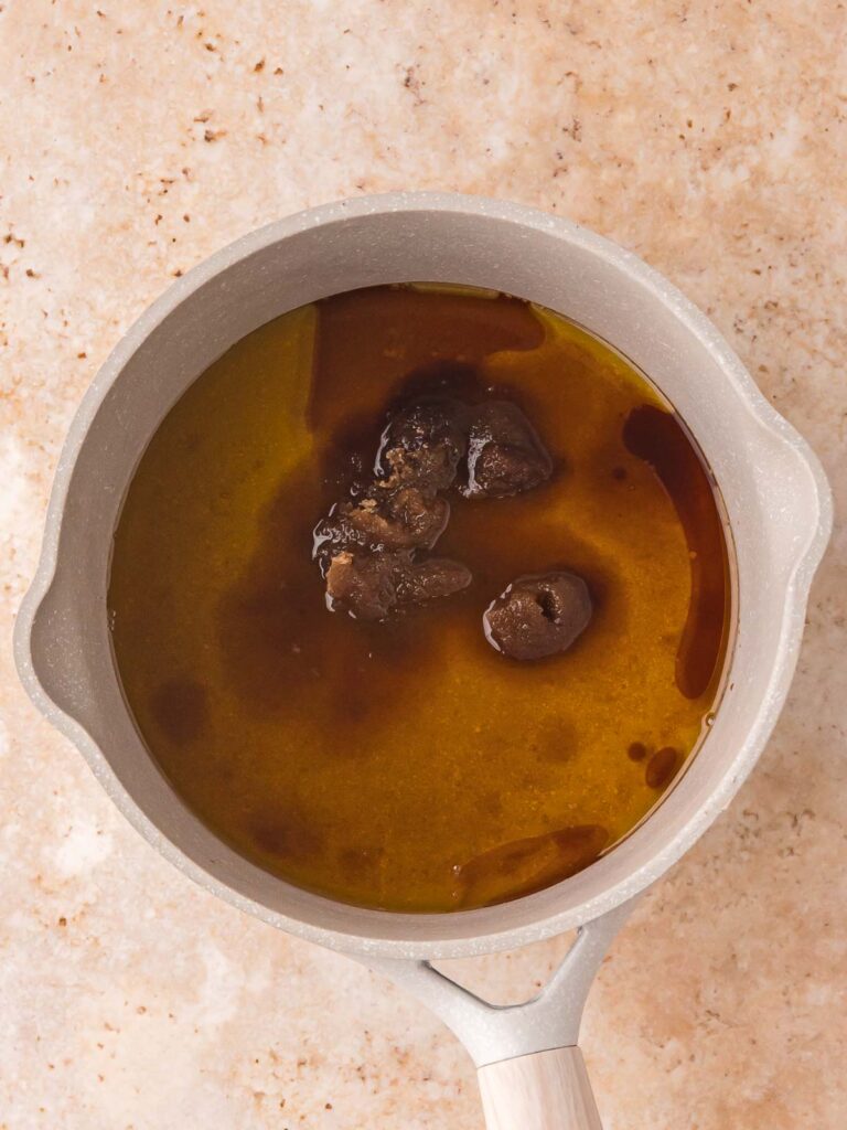 Saucepan with maple syrup, brown sugar, oil, and vanilla for pumpkin granola.