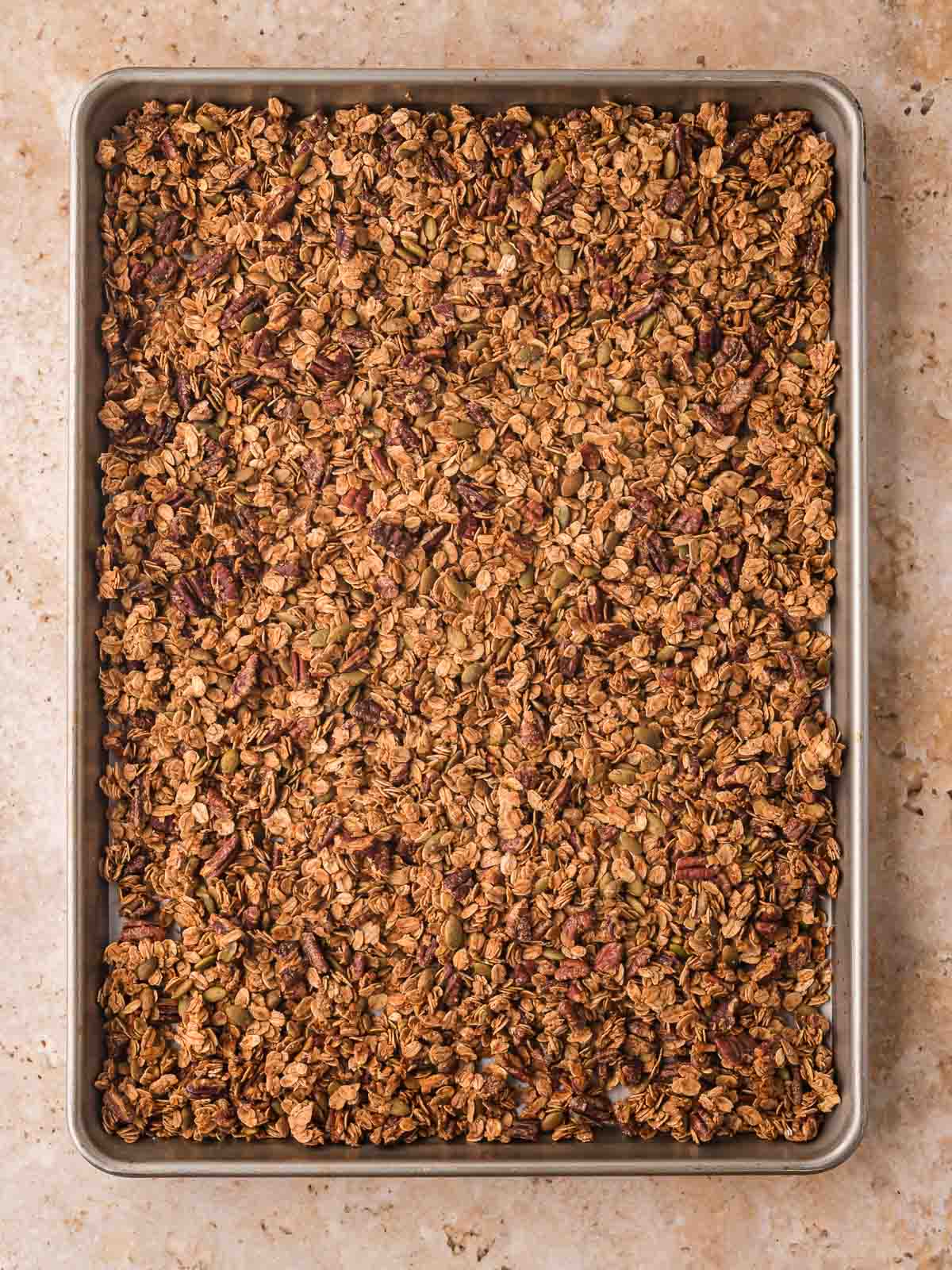 Golden baked pumpkin granola cooling on a baking sheet.
