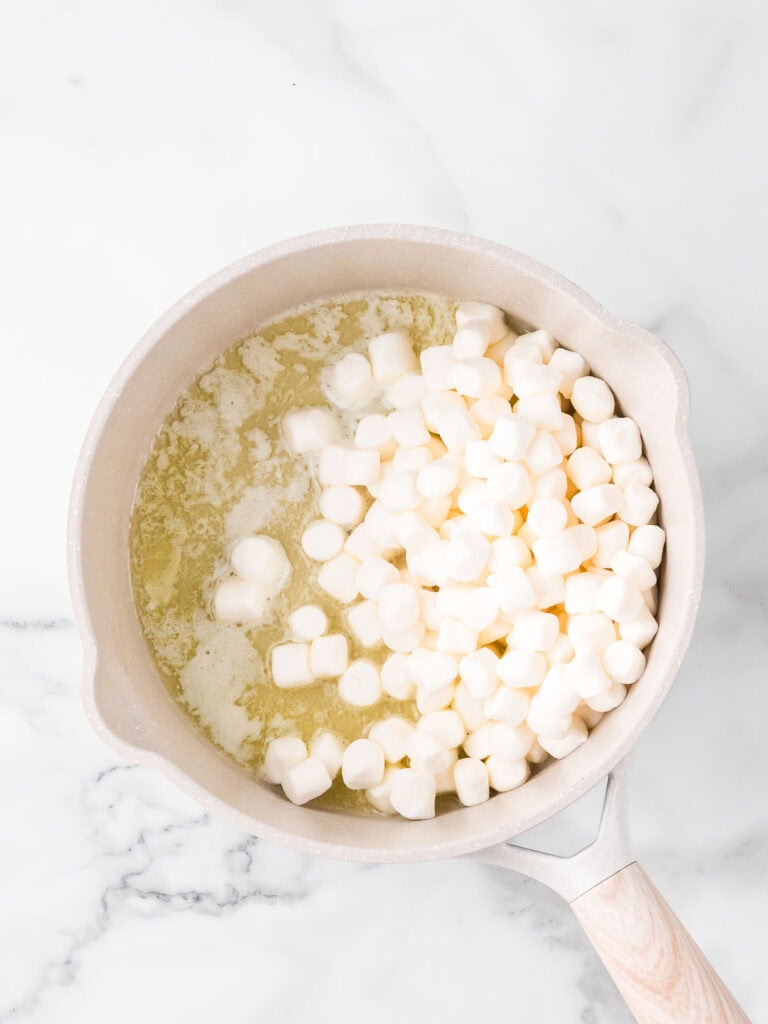 Melting mini marshmallows with butter in a saucepan for Rice Krispie Pumpkins.