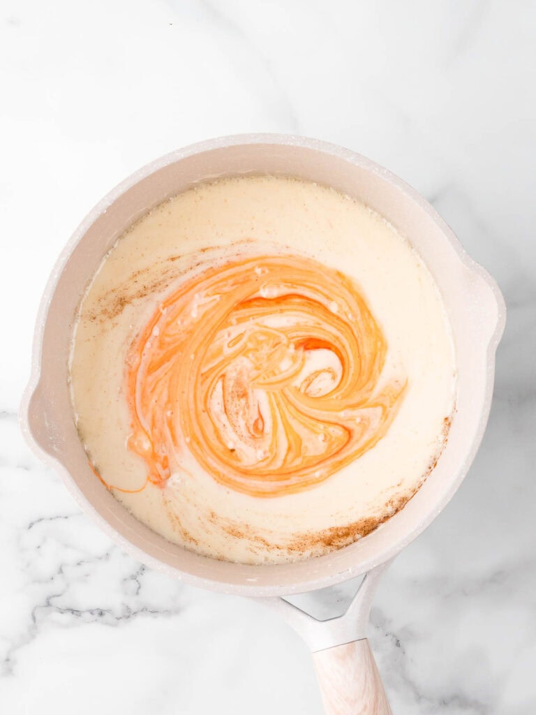Swirling orange food coloring into melted marshmallows for Rice Krispie Pumpkins.