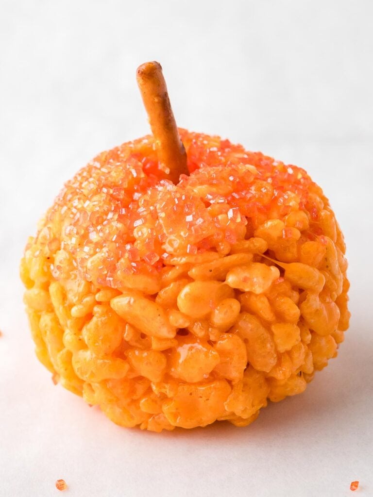 Rice Krispie Pumpkin decorated with orange sanding sugar and a pretzel stalk.