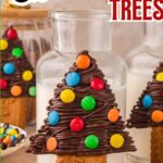 Decorated chocolate Christmas tree treats leaning against a glass of milk.