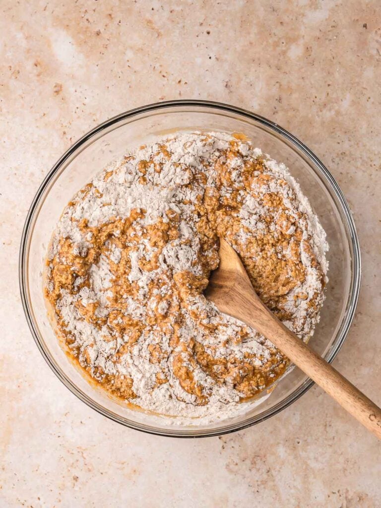 Dry and wet ingredients being combined with a wooden spoon to make Gingerbread Cake batter.