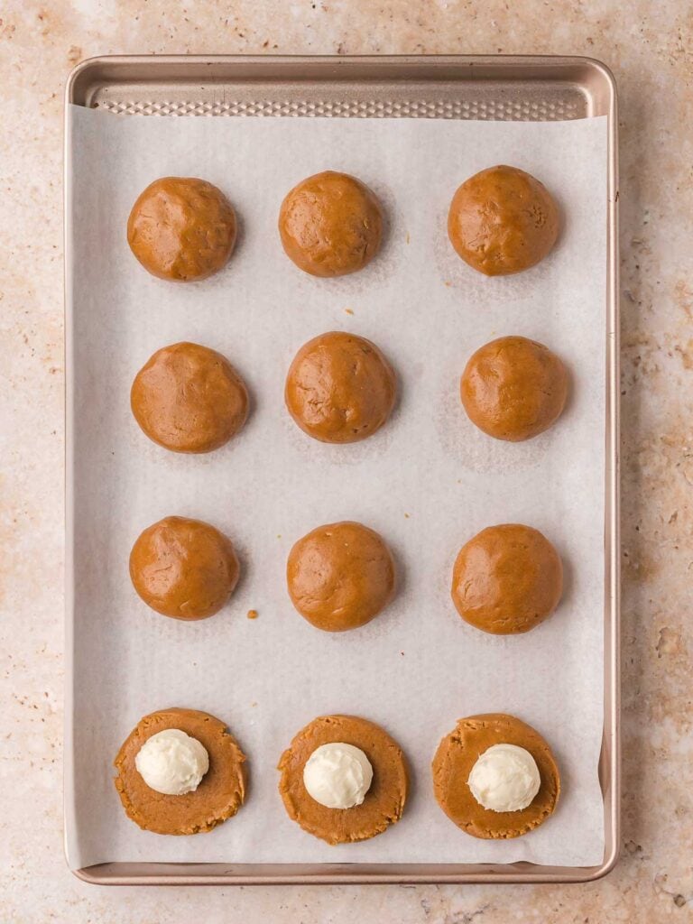 Gingerbread cookie dough balls formed with cheesecake filling enclosed inside, ready to bake.