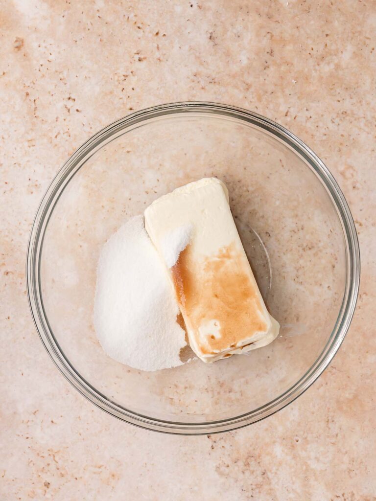 Cream cheese, sugar, and vanilla extract in a glass bowl ready to be mixed for the cheesecake filling for Gingerbread Cheesecake Cookies.