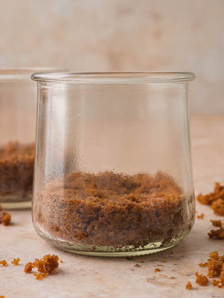 Crumbled gingerbread cake pressed into the bottom of a glass jar to form the base layer of the Mini Gingerbread Trifle.