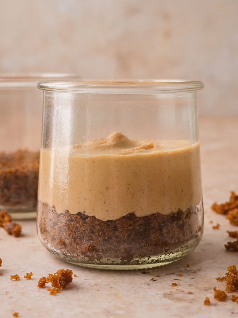 Spiced cheesecake filling added over the gingerbread cake base in a clear glass jar for the Mini Gingerbread Trifle.