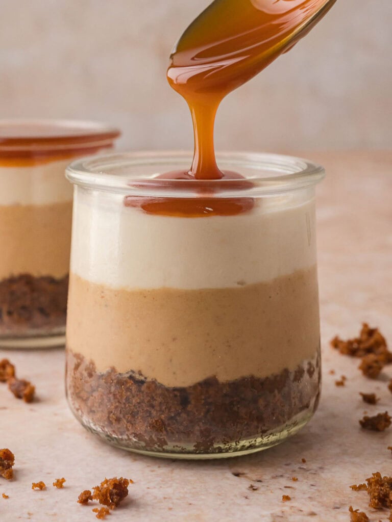 Caramel sauce being drizzled over the top of the whipped cream layer for the Mini Gingerbread Trifle.