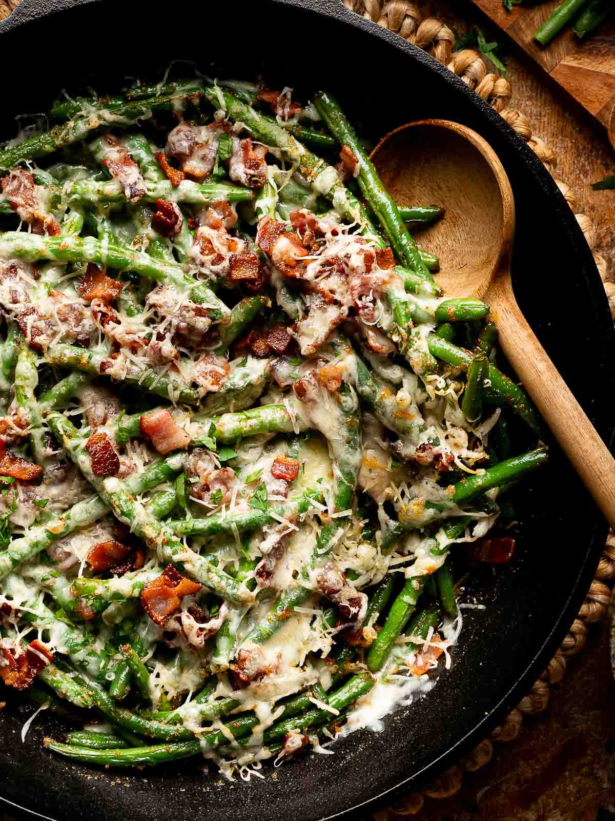 Cheesy green beans with garlic and bacon in skillet ready to serve for dinner.