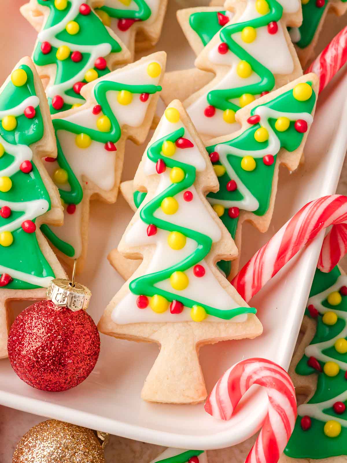 Easy Christmas Sugar Cookies arranged on a white tray with red and white candy canes and festive decorations.