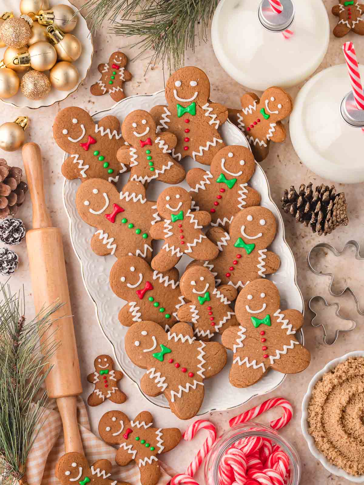 Plate of decorated Gingerbread Man Cookies with icing details surrounded by milk bottles, candy canes, and Christmas decorations.