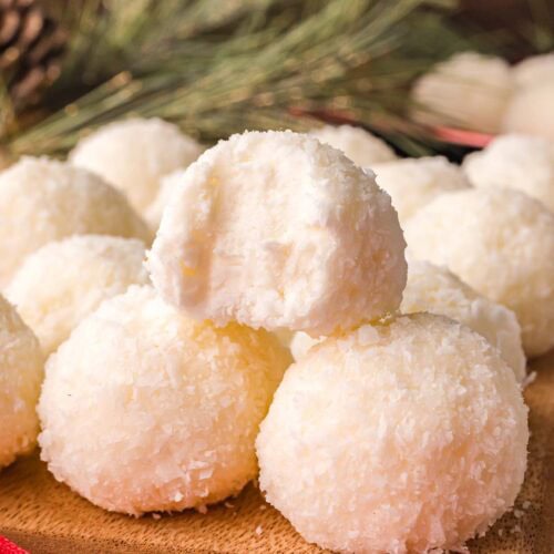 Soft and creamy Coconut Snowball Cookies with a bite taken out, showing the fluffy coconut texture inside.