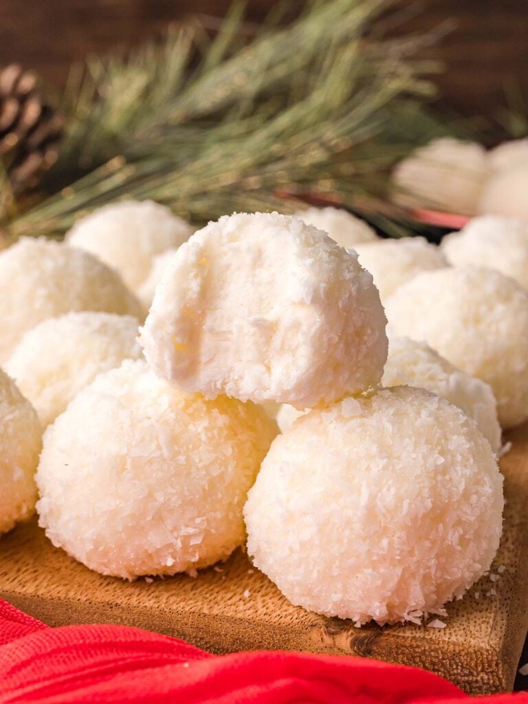 Soft and creamy Coconut Snowball Cookies with a bite taken out, showing the fluffy coconut texture inside.