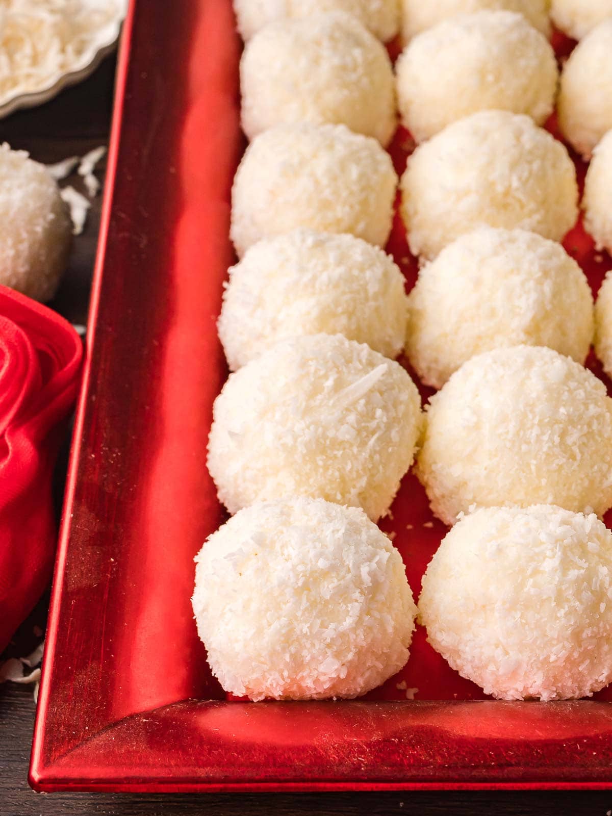 Coconut Snowball Cookies displayed in neat rows on a red holiday tray, ready to serve for Christmas dessert platters.