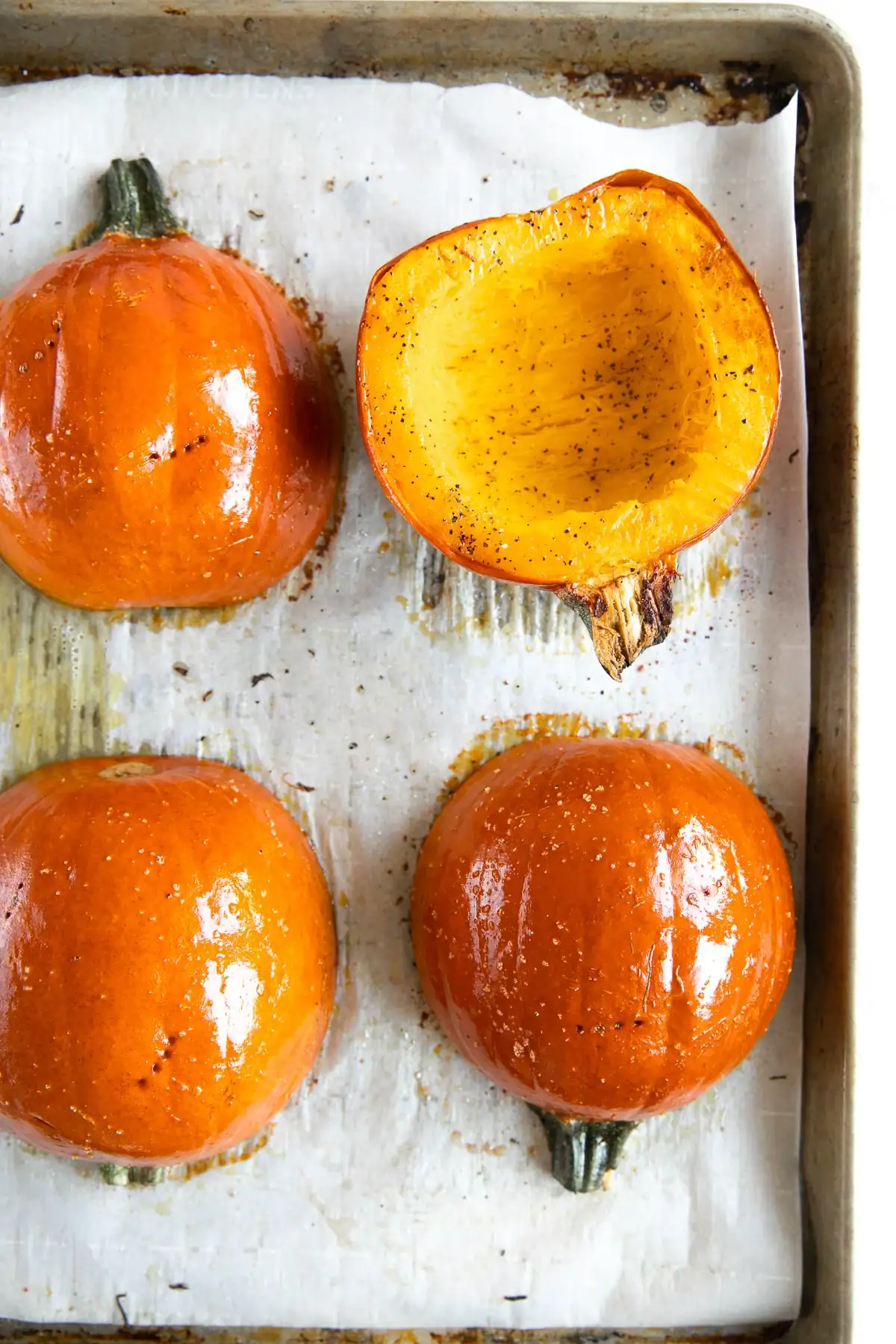 Two Pumpkins cut in half and on a baking sheet ready for roasting.