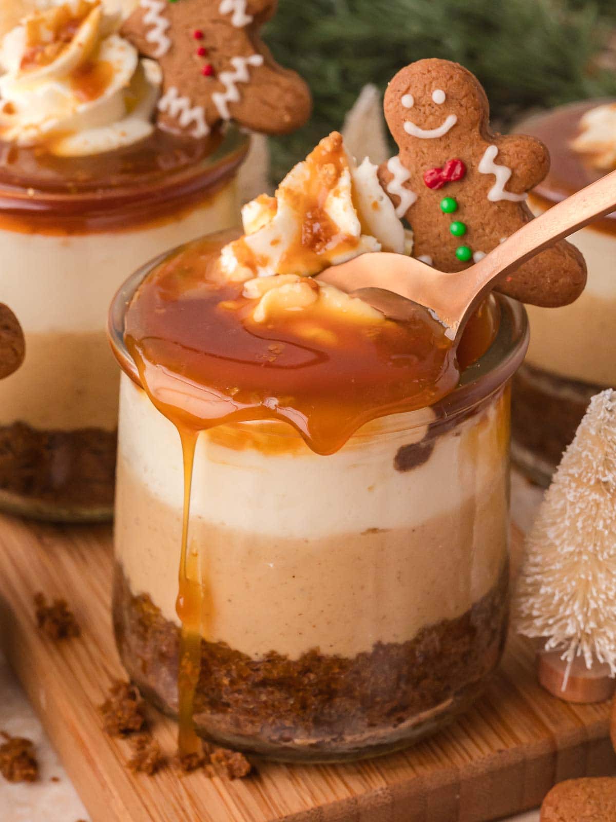 Spoon dipping into a Mini Gingerbread Trifle showing the creamy layers of cheesecake, caramel, and gingerbread cake with caramel dripping down the side.