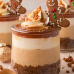 Mini Gingerbread Trifle in a glass jar with layers of gingerbread cake, spiced cheesecake filling, whipped cream, caramel, and a mini gingerbread man cookie on top.