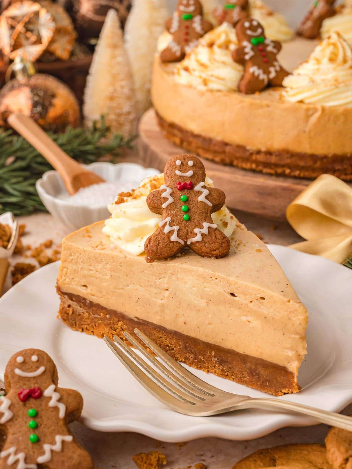 Slice of creamy No Bake Gingerbread Cheesecake on a white plate with whipped cream and a mini gingerbread cookie on top.