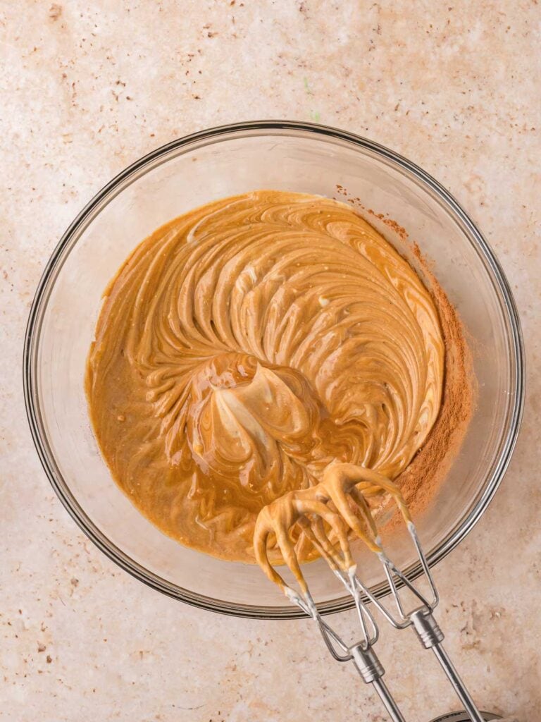 Gingerbread cheesecake filling with molasses and spices after being mixed with electric beaters.