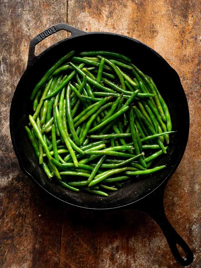 Fresh green beans added to a skillet for cheesy bacon green beans.