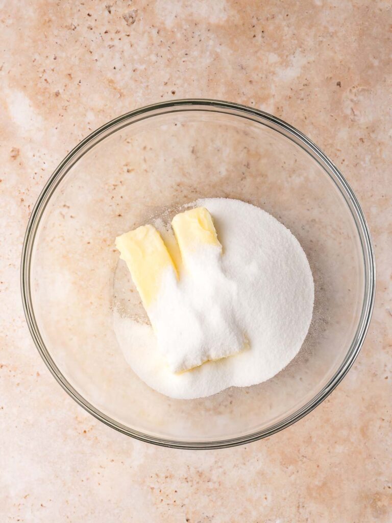 Softened butter and sugar in a glass bowl ready to be creamed for Christmas sugar cookies.