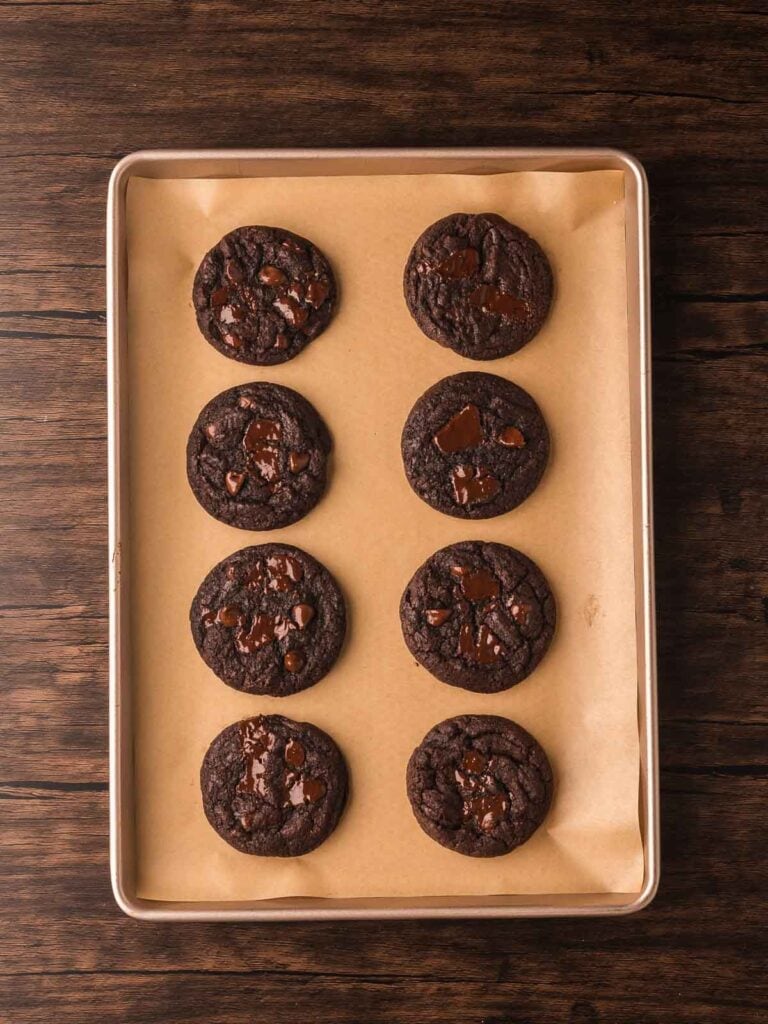 Freshly baked Double Chocolate Chunk Cookies with melty dark chocolate chunks cooling on a baking sheet.