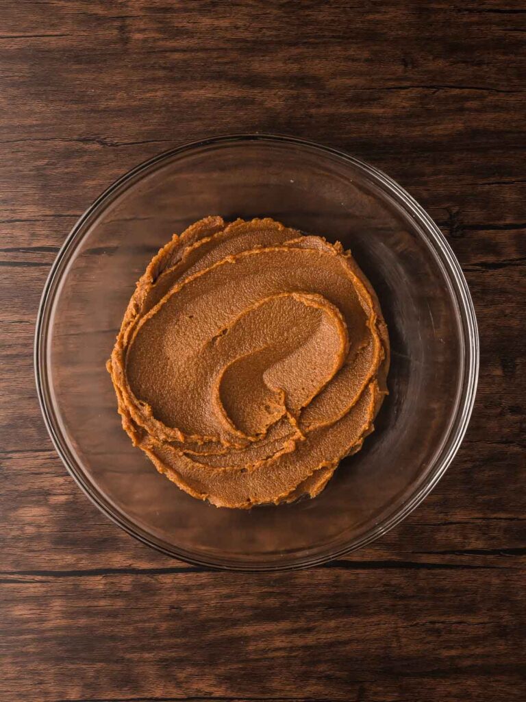 Melted butter mixed with brown and white sugar until smooth in a glass bowl for Double Chocolate Chunk Cookies.