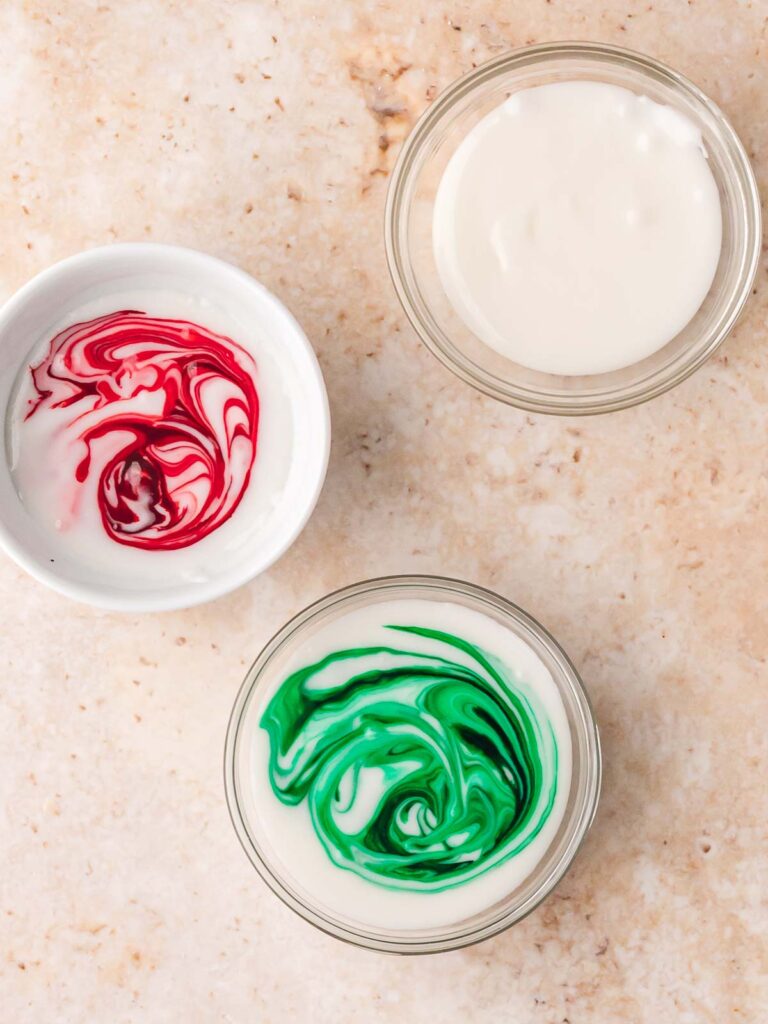 Bowl of white icing for Gingerbread Man Cookies with red and green food coloring swirled in.