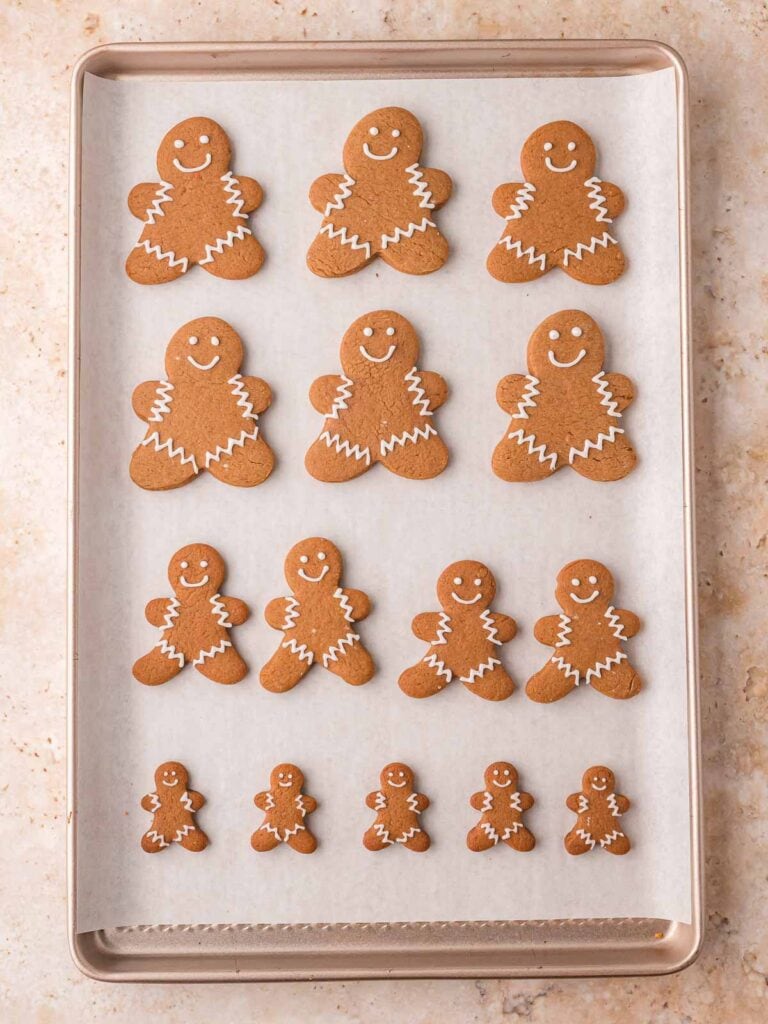 Baking sheet of freshly baked Gingerbread Man Cookies with white icing.