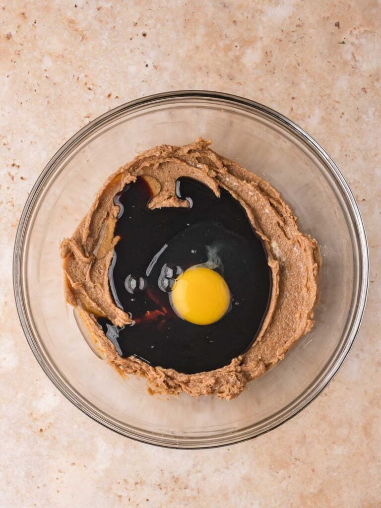 Bowl with egg, molasses, and creamed butter mixture for Gingerbread Man Cookies.